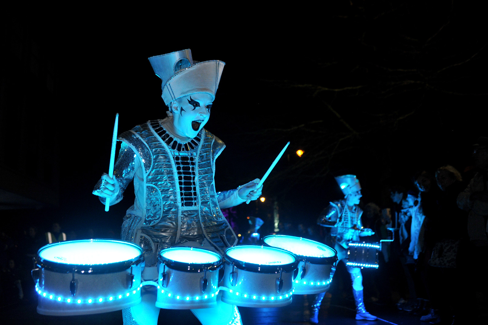 Spark! street drumming band illuminated in white light