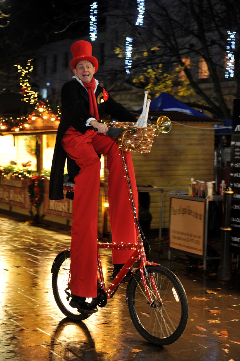Street performing riding bike with stilts 