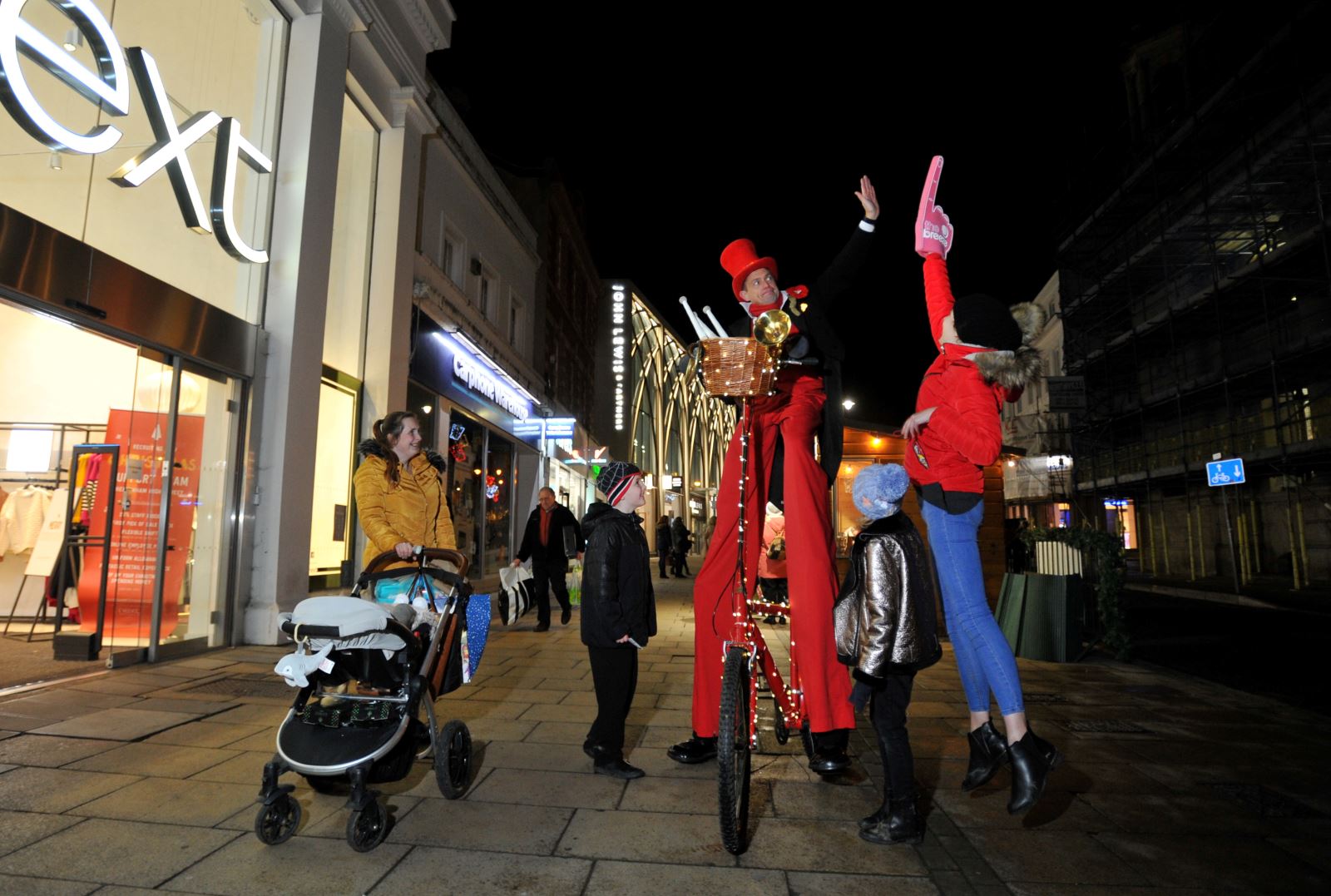 Street performer on stilts on bike outside Next on Cheltenham High Street
