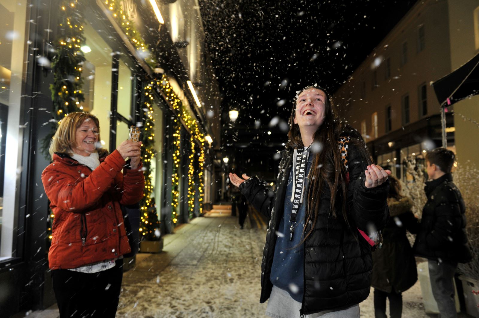 Woman taking picture of child enjoying a snow machine