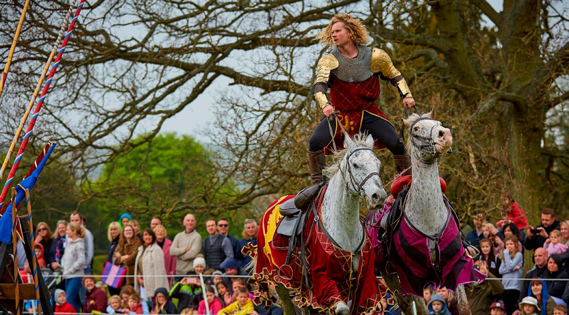 Man standing up and riding two horses at once