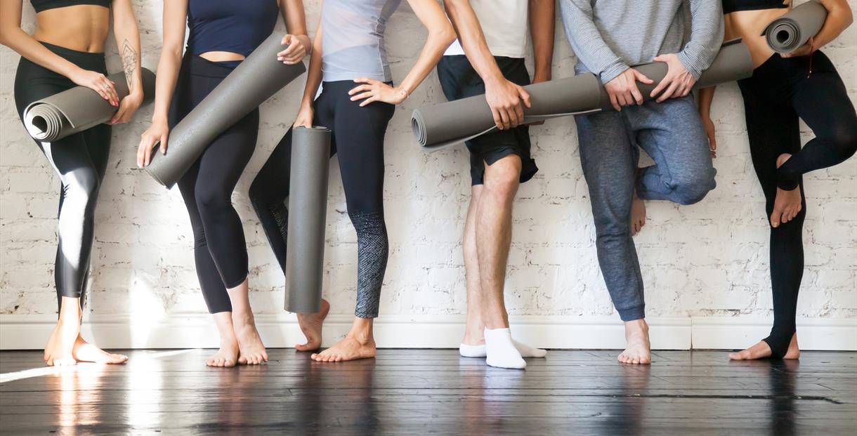 People holding yoga mats in gym gear