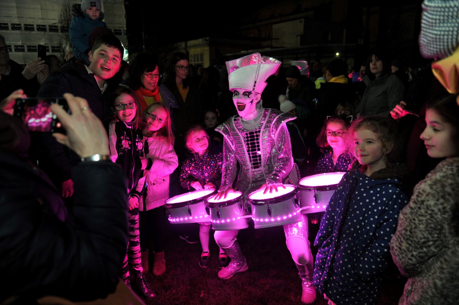 Spectators beside a Spark! performer who is illuminated in purple light