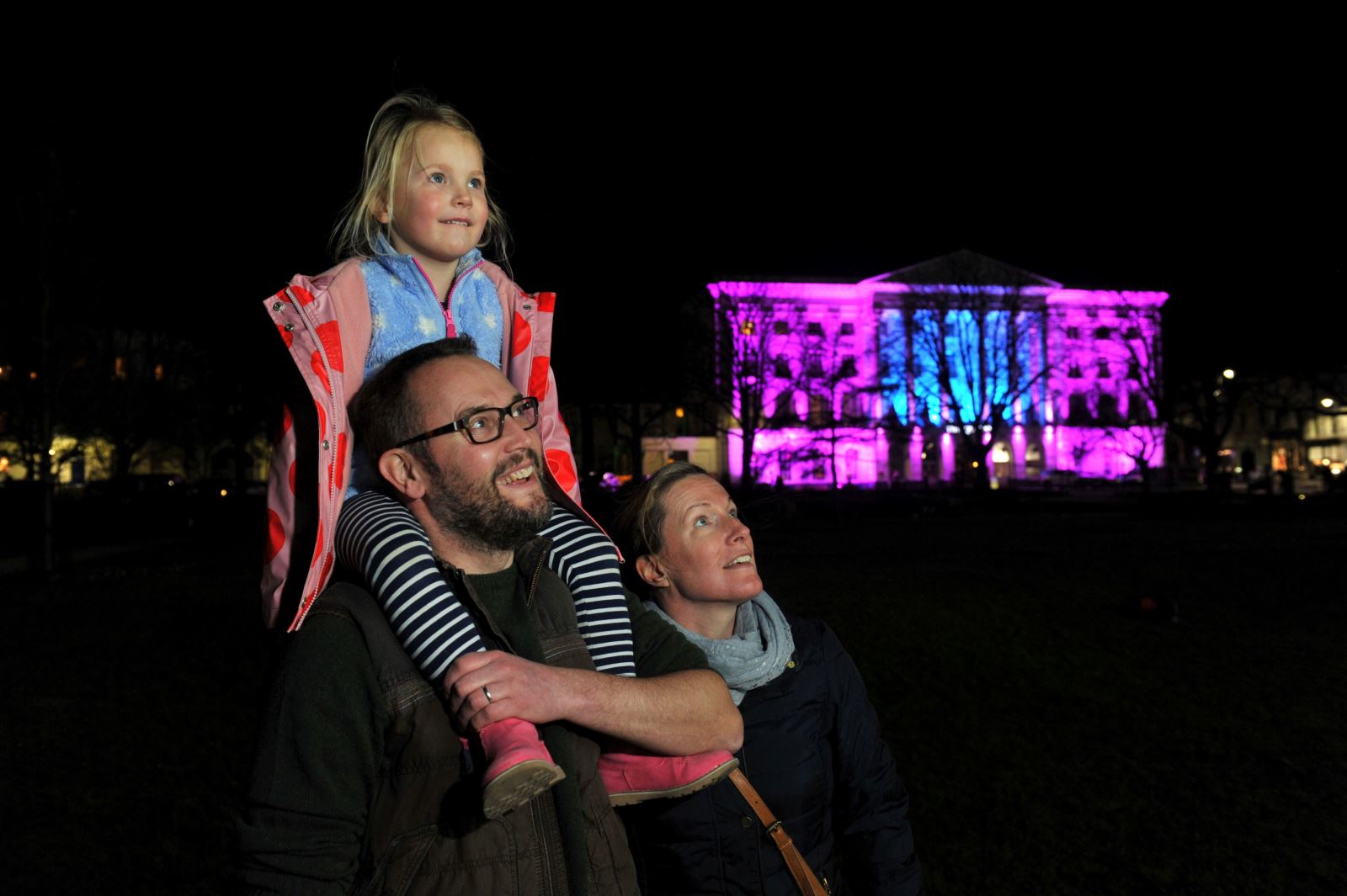 A child on her father's shoulder who is beside her mother whilst enjoying the Spark! performance