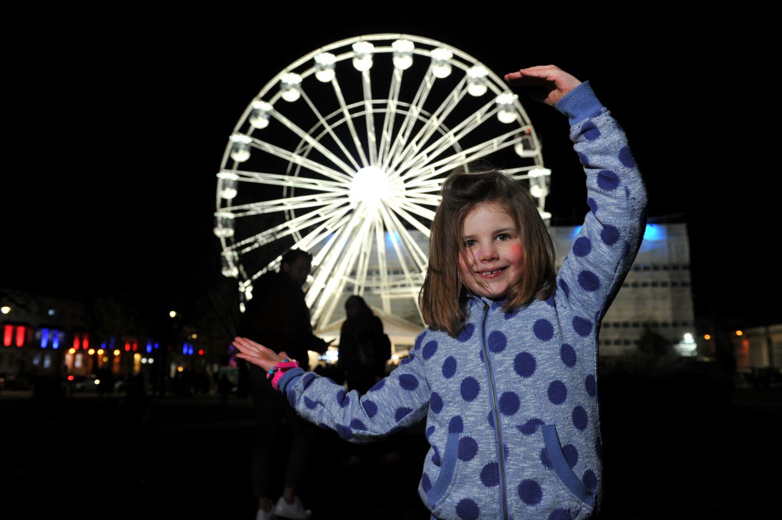 A child in front of a giant illuminated Ferris wheel