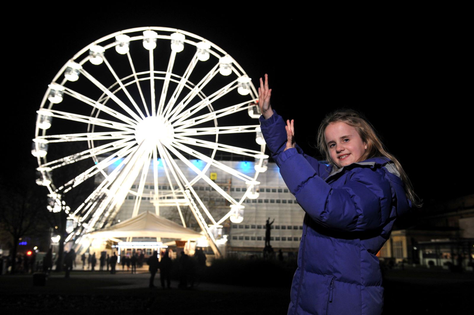 A child pretending to support the Ferris wheel with her hands