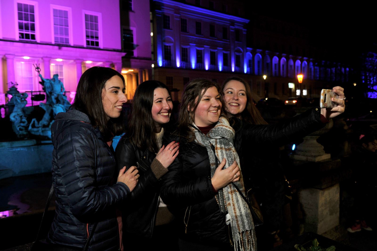 Spectators taking a selfie in front of a lit up Neptune's Fountain