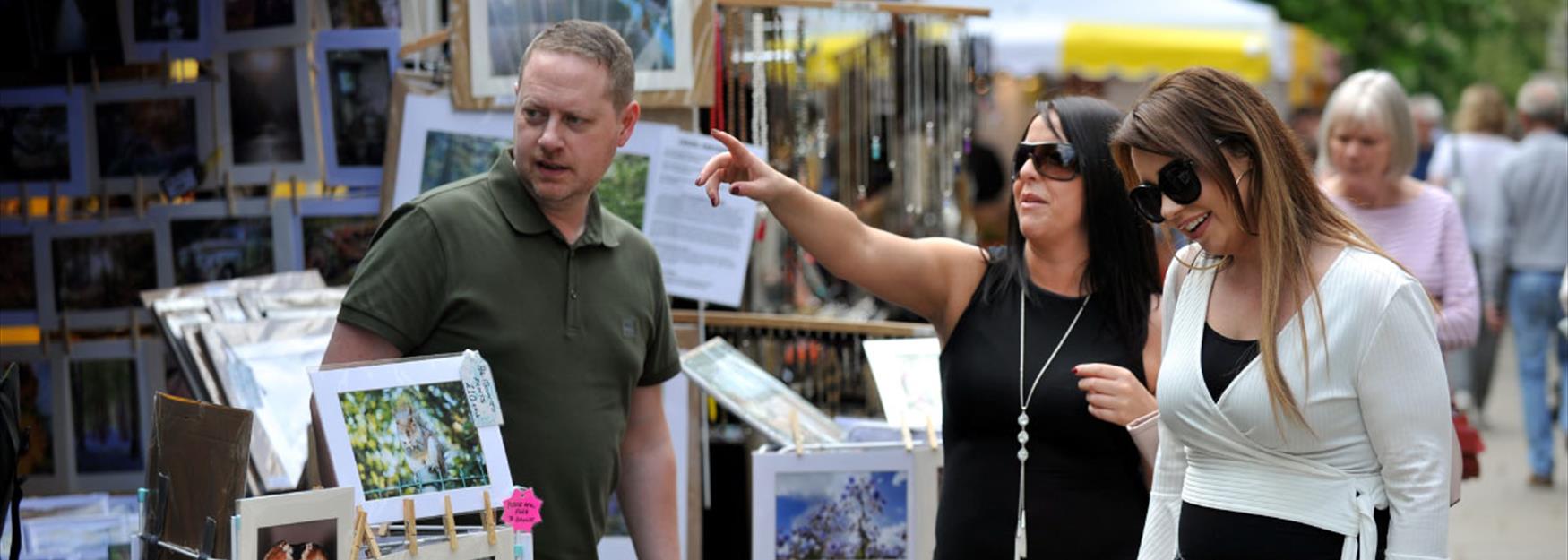 Two women browsing an art stall at a Cheltenham craft market