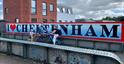 Family cycling along the Honeybourne Line in Cheltenham, with Cheltenham Paint Festival murals in background