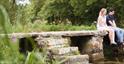 Couple sitting on a low bridge over a stream